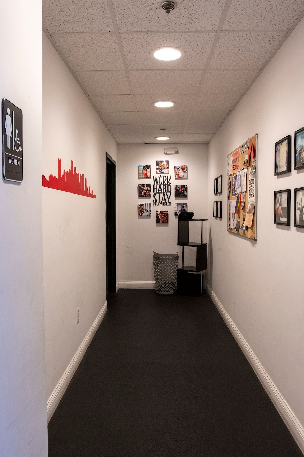 A hallway with pictures on the wall and a trash can
