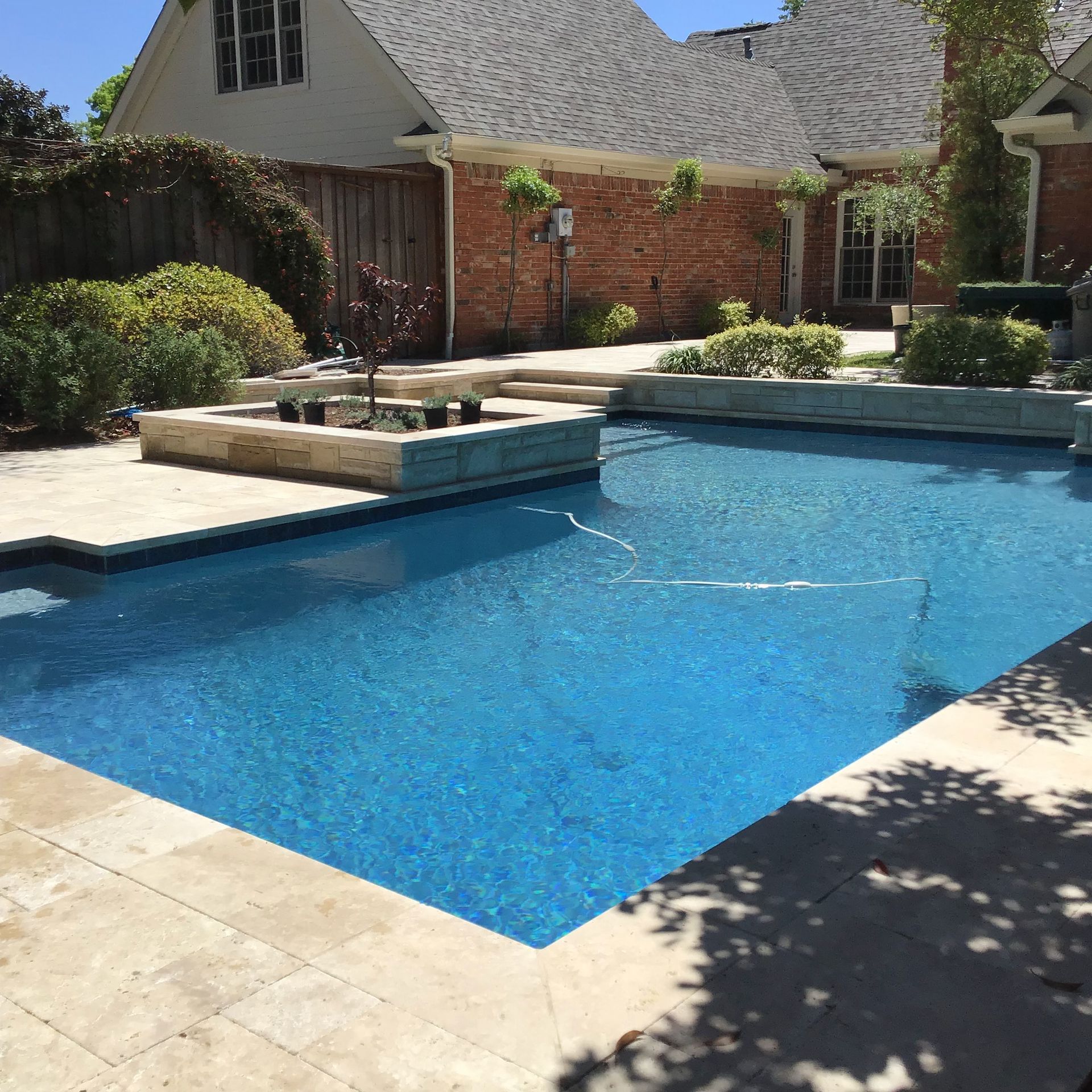 A large swimming pool in front of a brick house