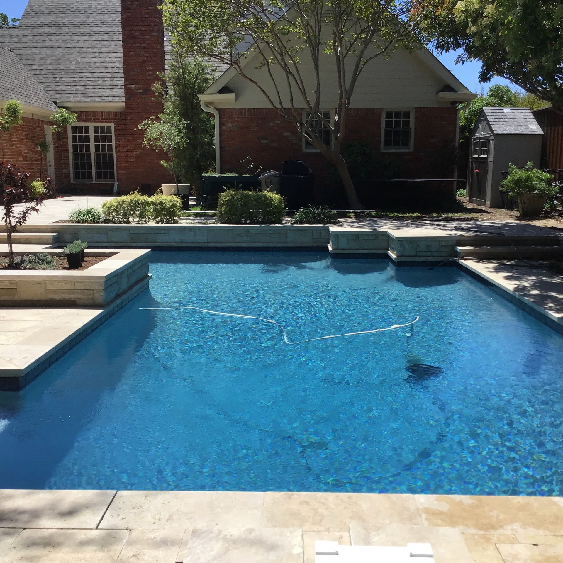 A large swimming pool in front of a brick house