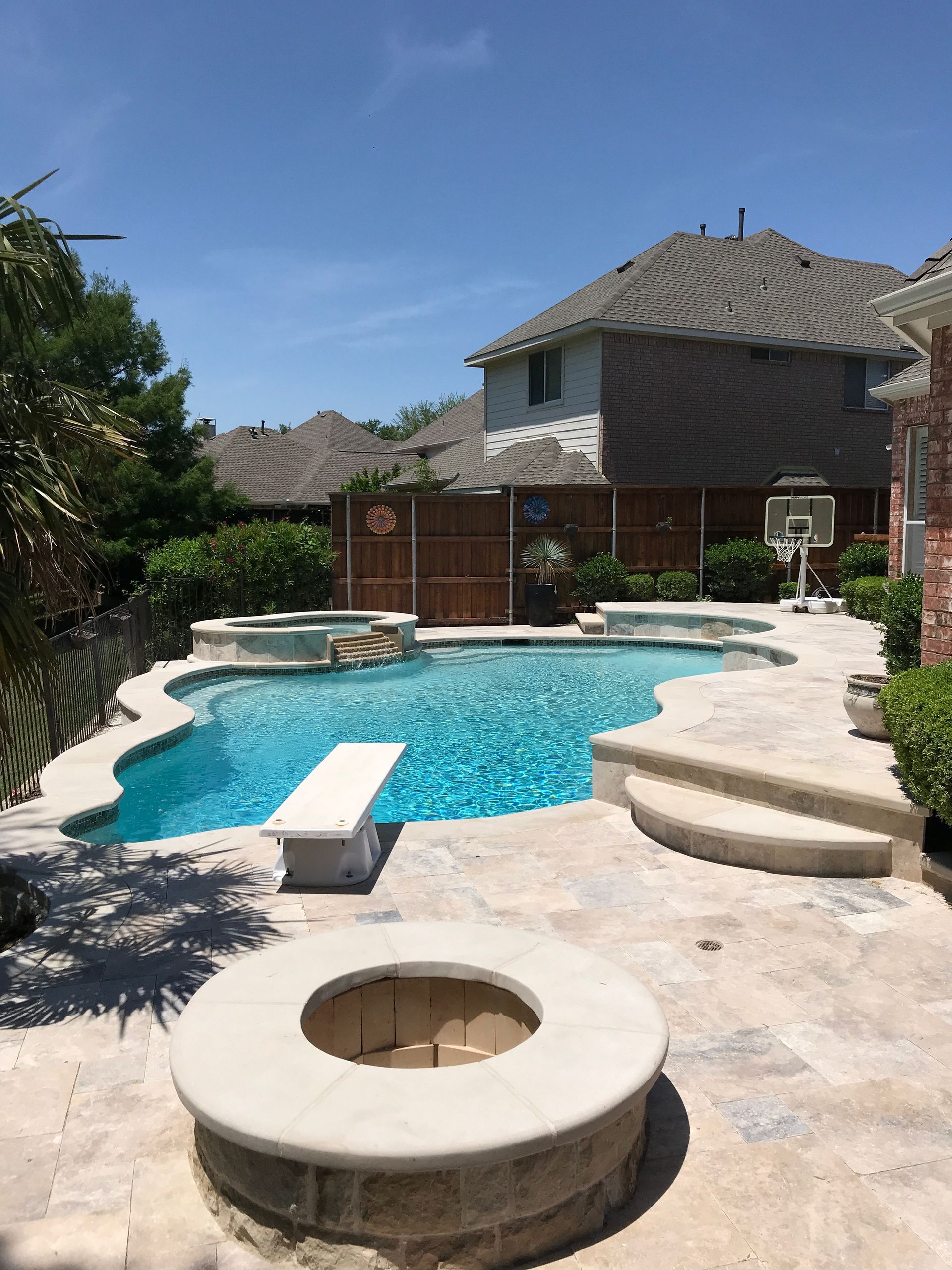 A large swimming pool with a fire pit in front of a house.