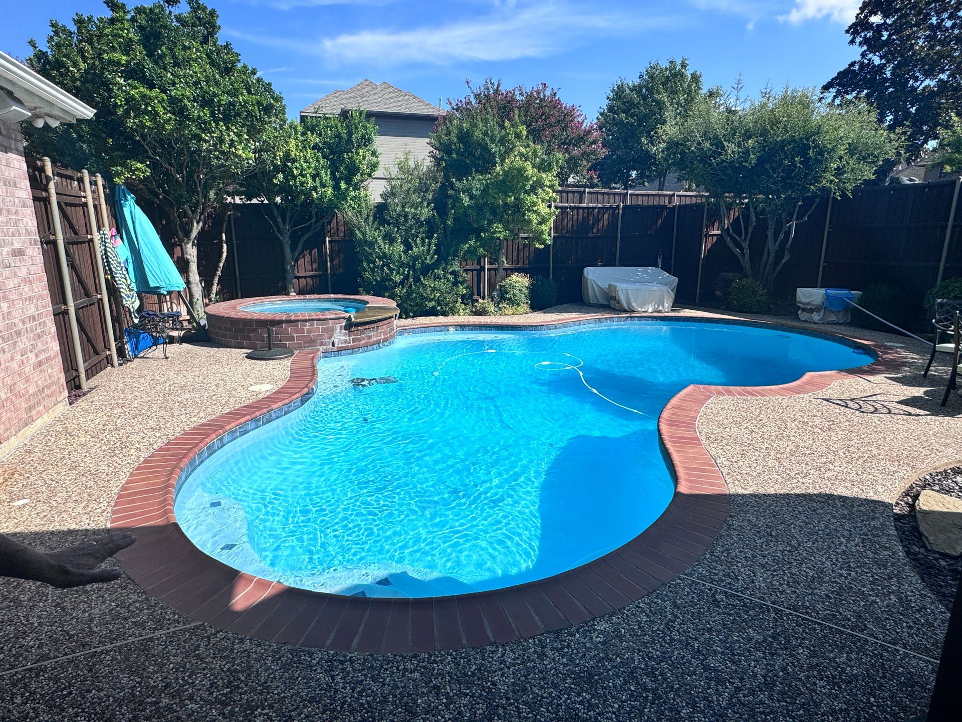 There is a large swimming pool in the backyard of a house.