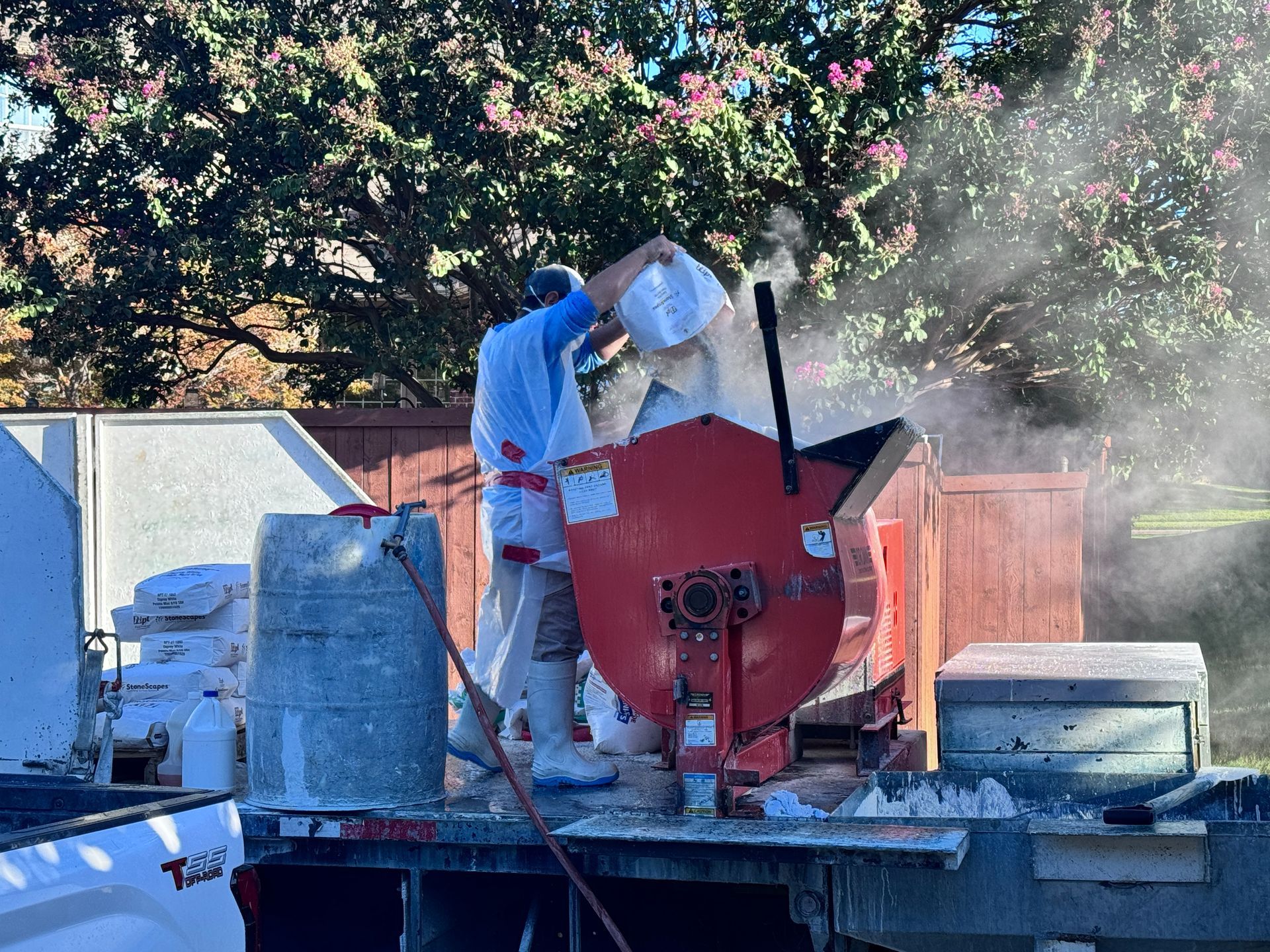 A man is pouring concrete into a mixer on the back of a truck.