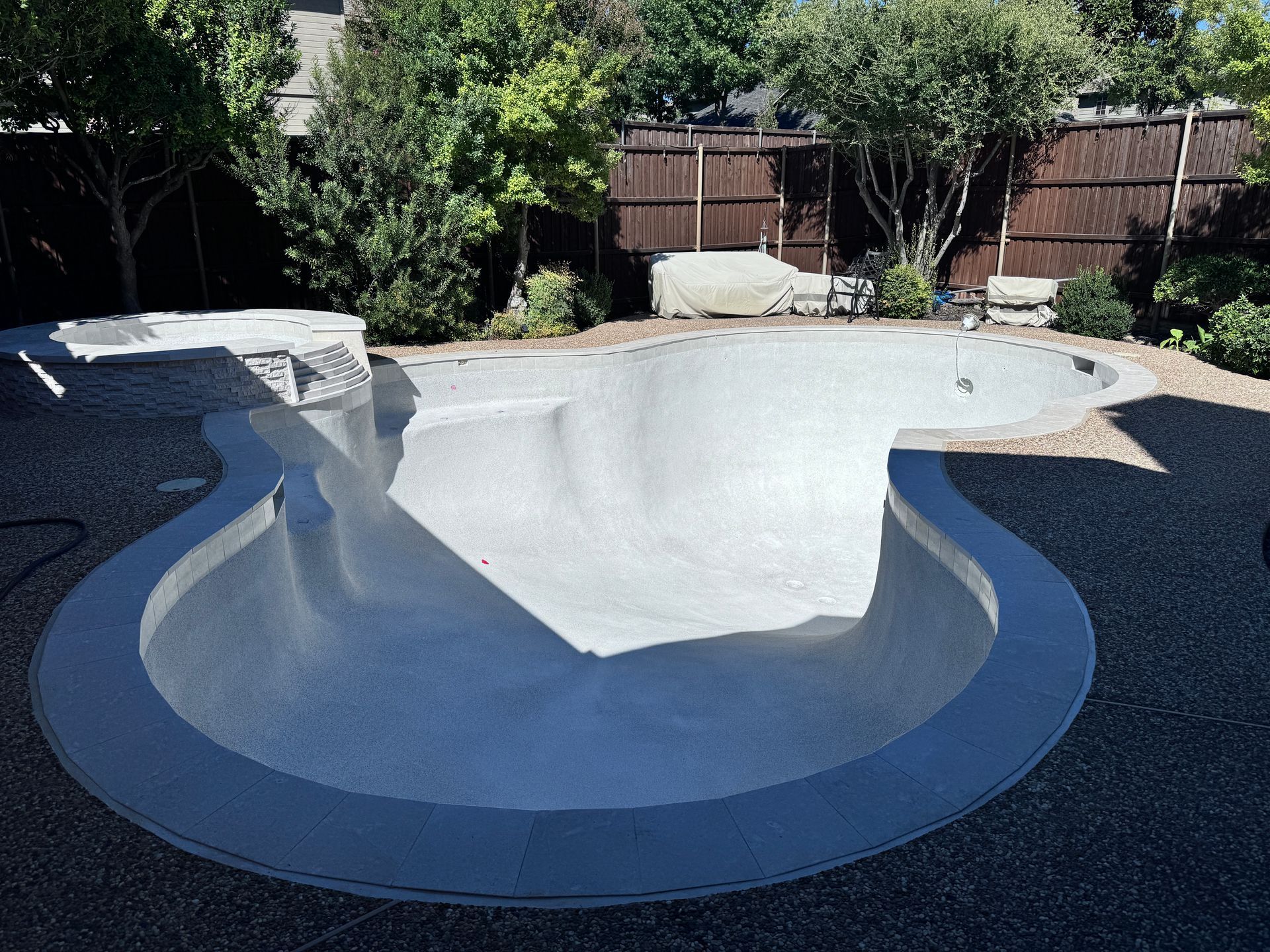 A large swimming pool in a backyard with a wooden fence in the background