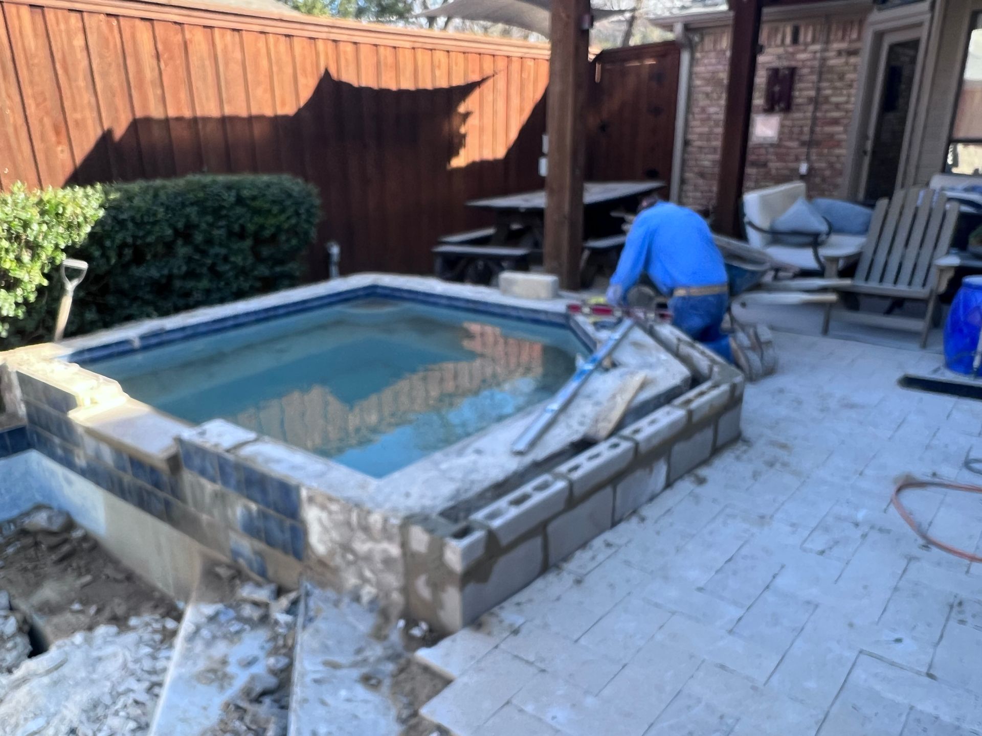 A man is working on a hot tub on a patio.