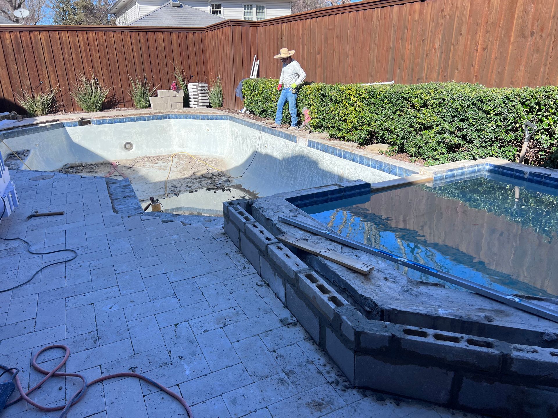 A man is standing next to a swimming pool that is being remodeled.