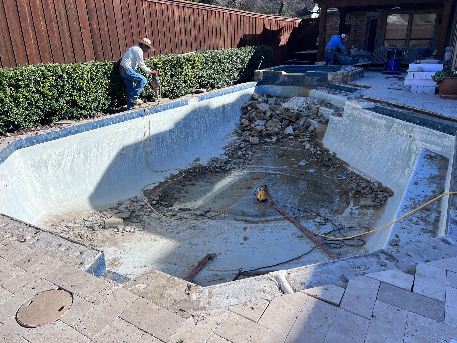 A man is working on a swimming pool that is being remodeled.