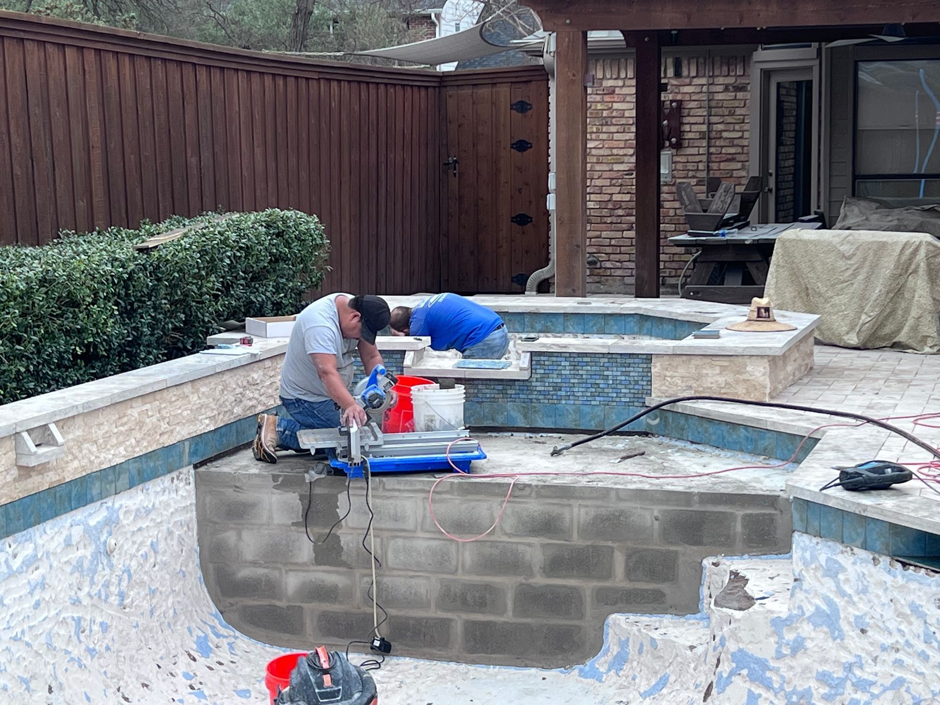 A man is working on a swimming pool with a vacuum cleaner.