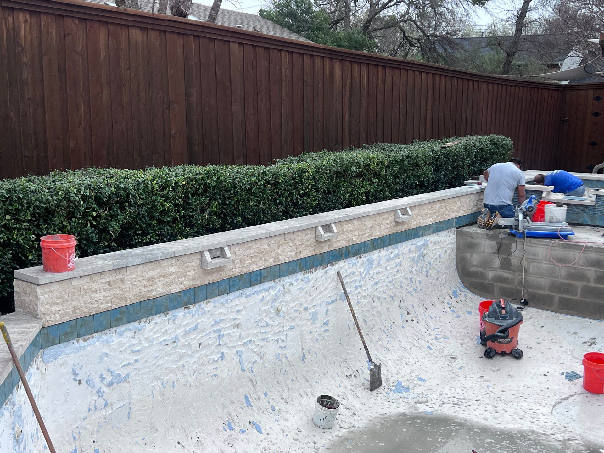 A man is working on the side of a swimming pool.