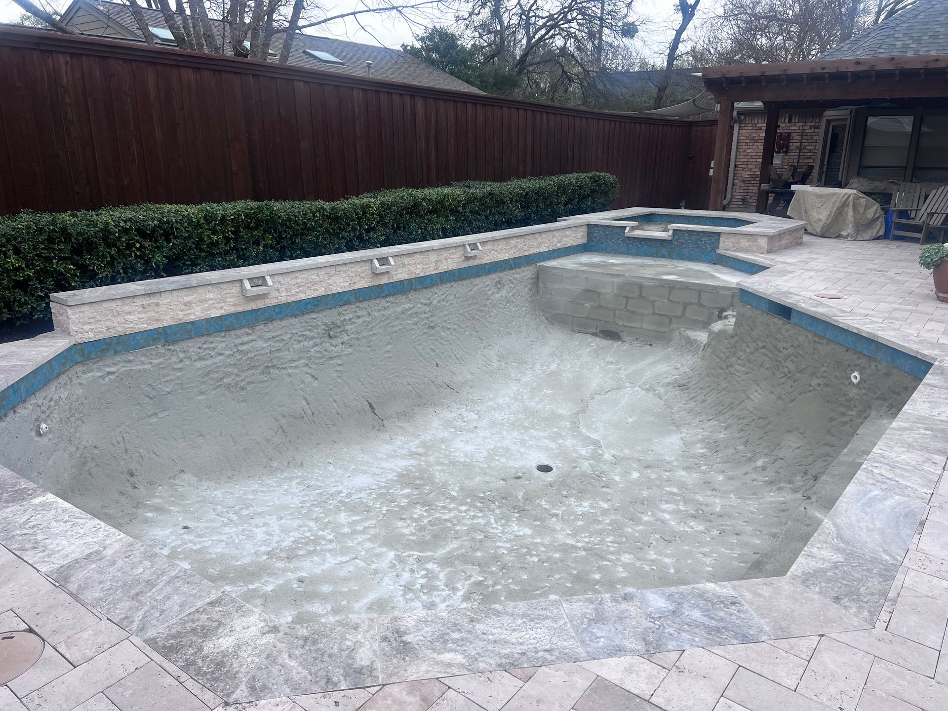 An empty swimming pool with a wooden fence in the background