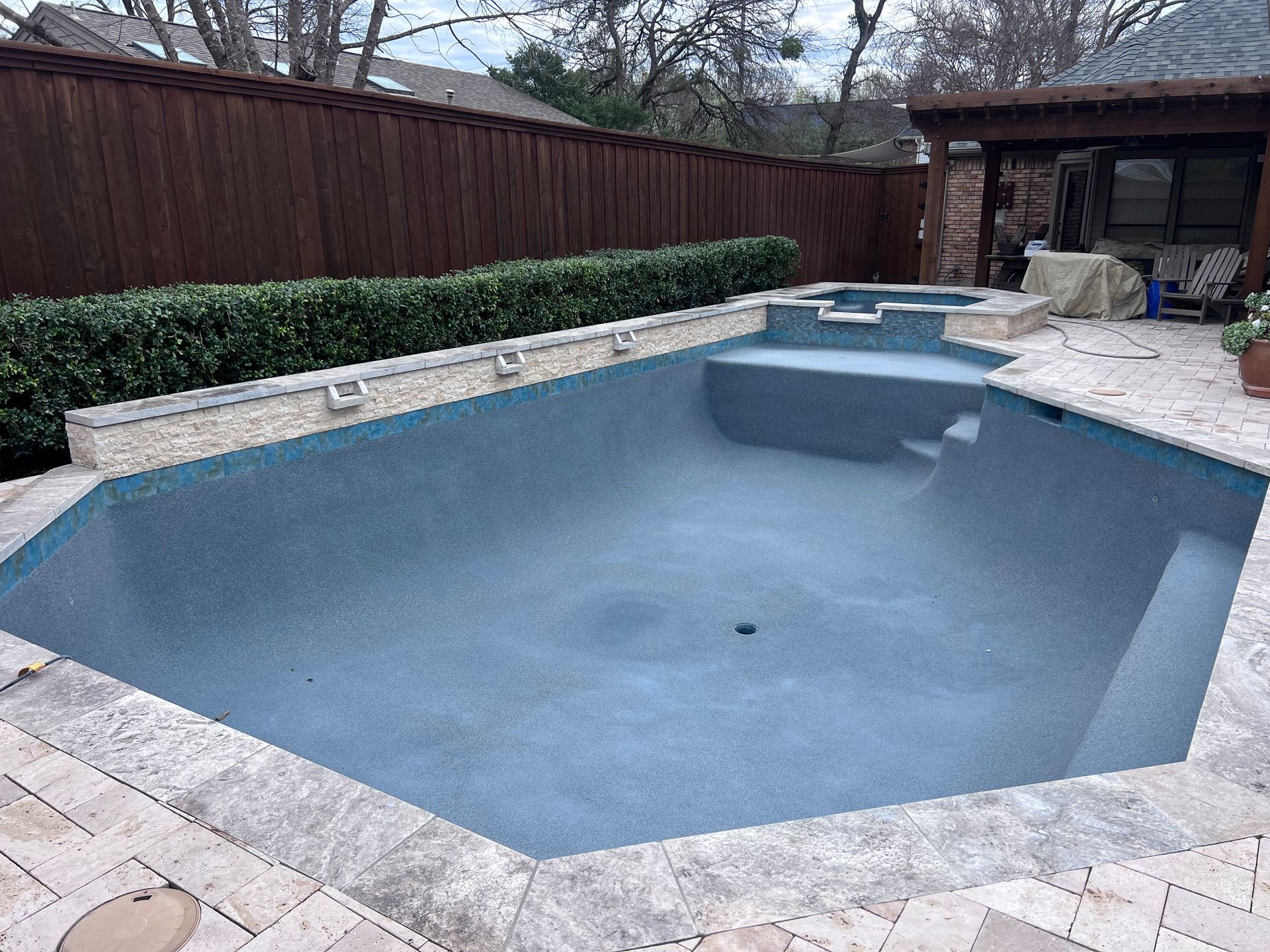 A large swimming pool with a wooden fence in the background.