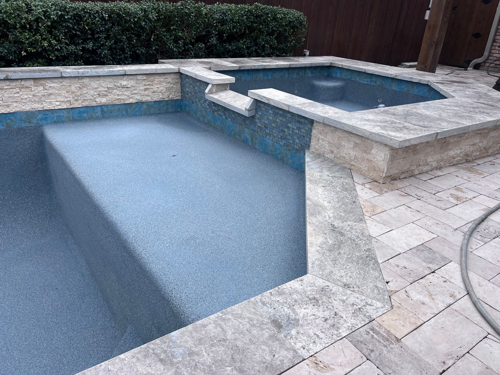 A large swimming pool with a hot tub in the backyard.