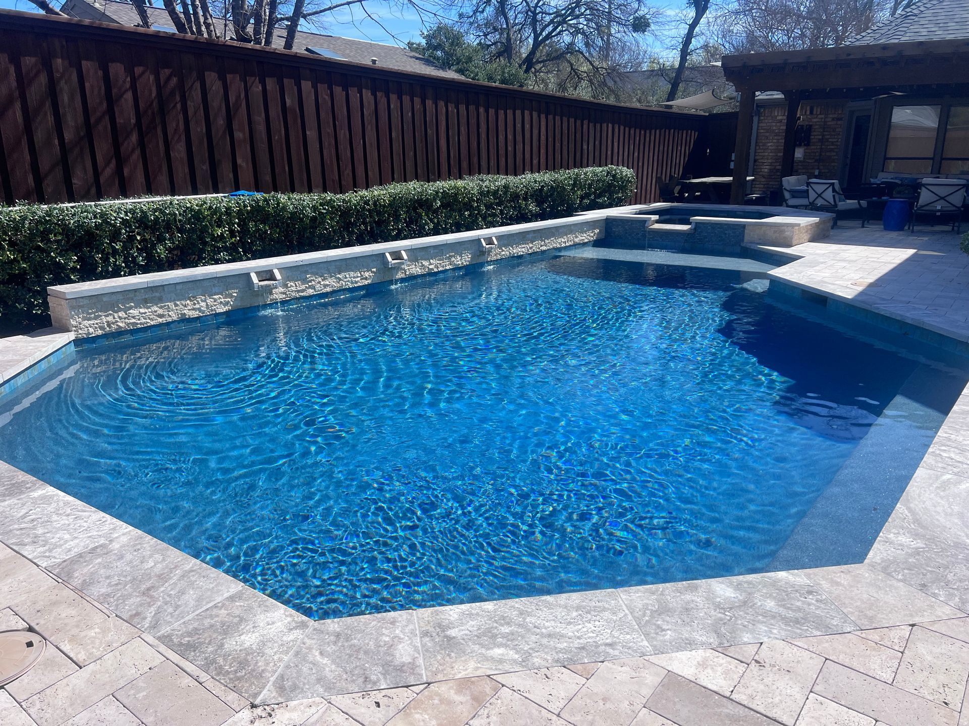 A large swimming pool with a wooden fence in the background.