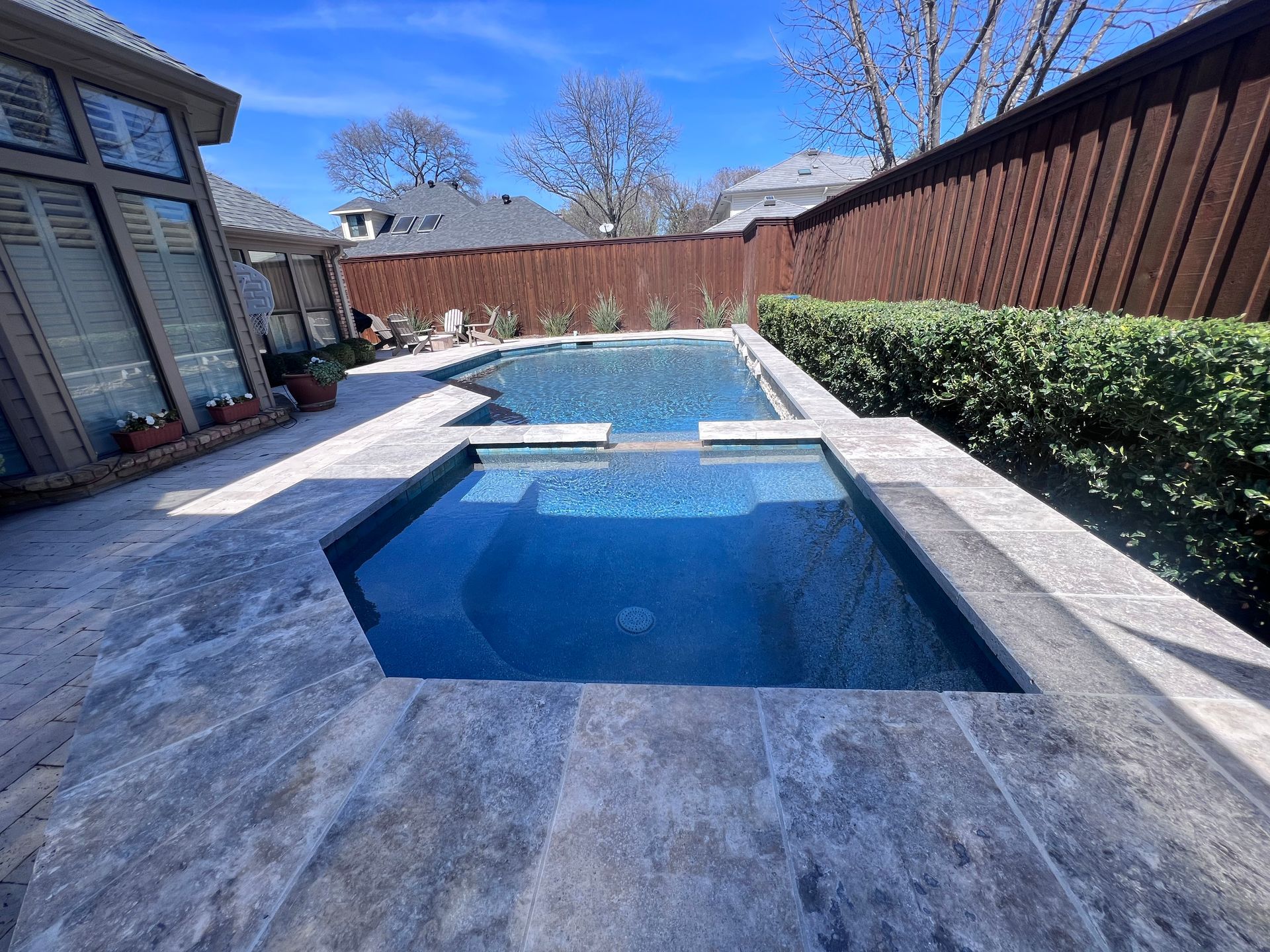 There is a large swimming pool in the backyard of a house.