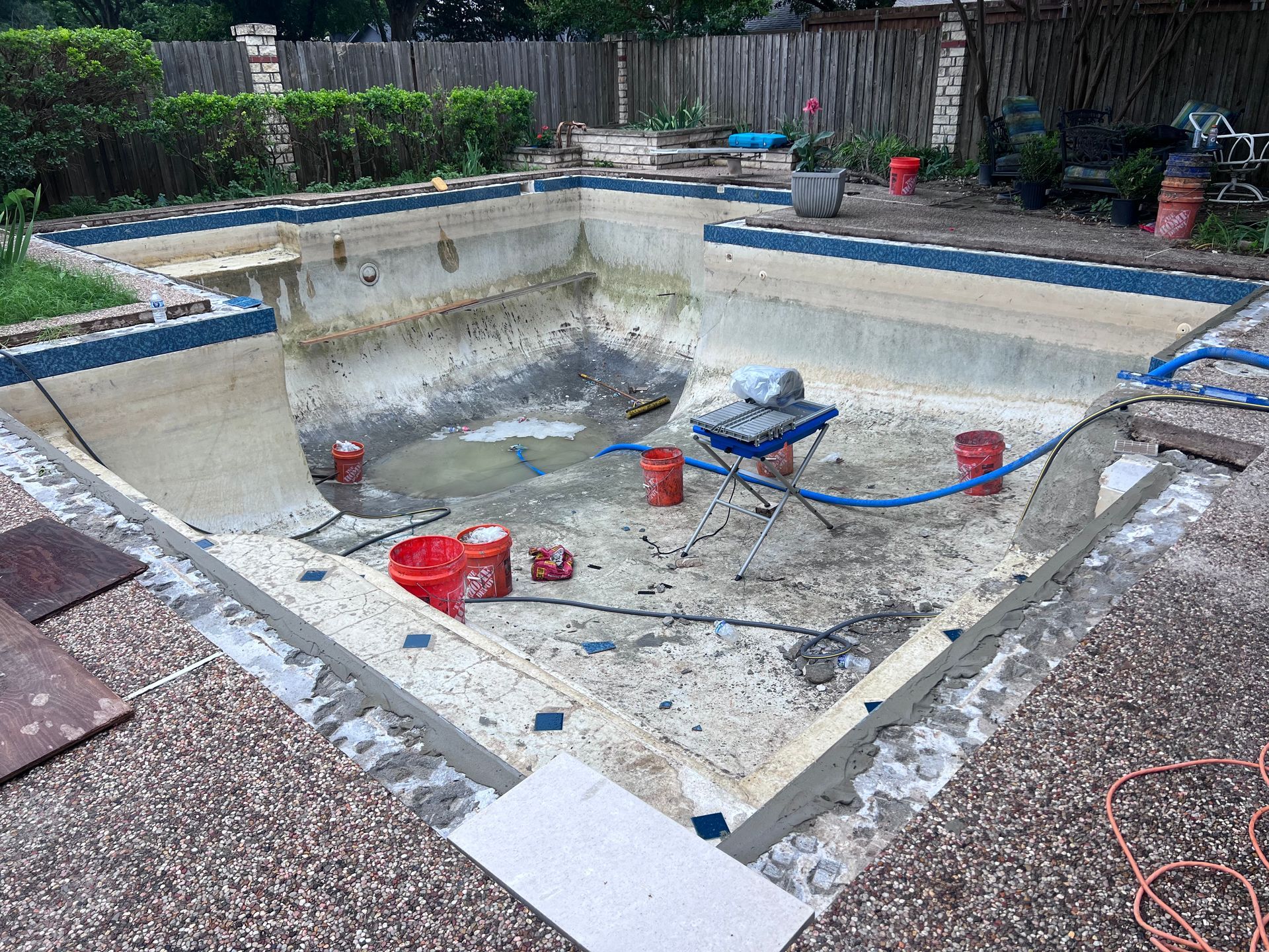 A swimming pool is being remodeled in a backyard.