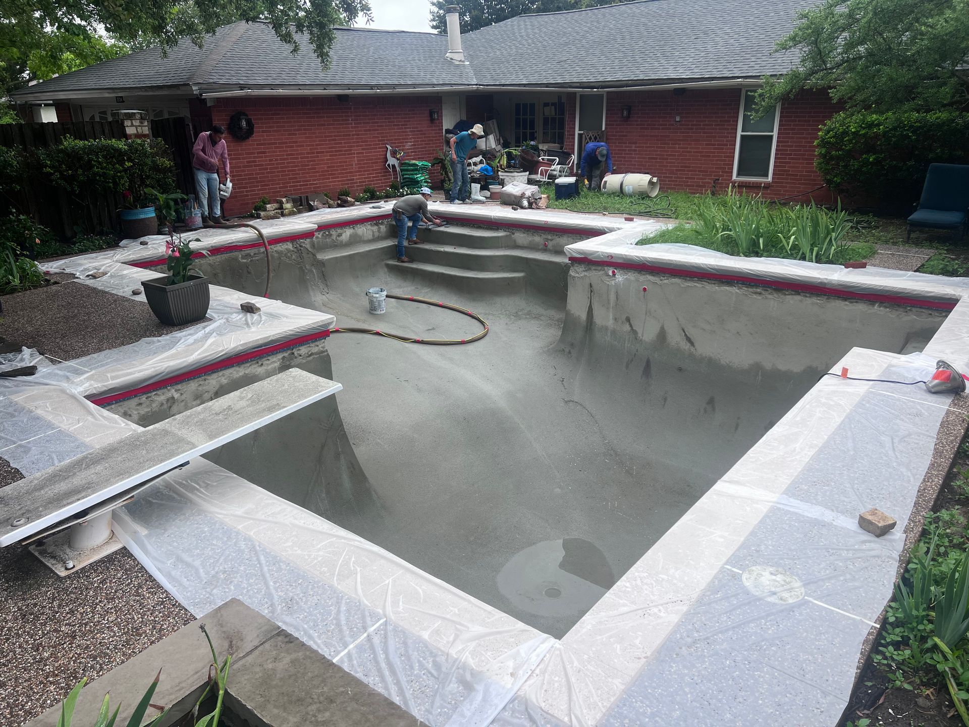 A swimming pool is being built in the backyard of a house.