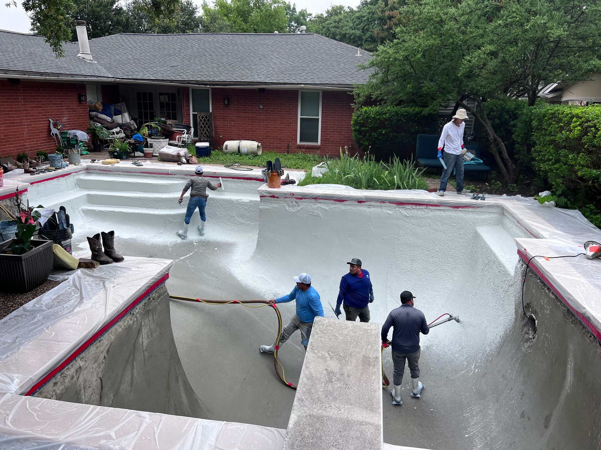 A group of people are working on a swimming pool in a backyard.