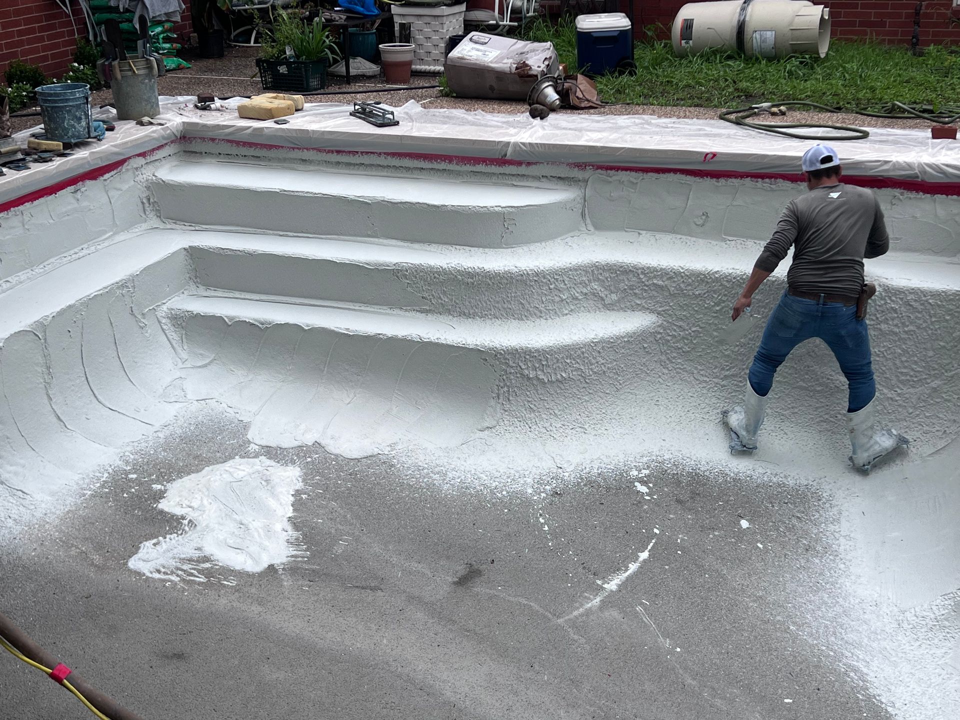 A man is painting a swimming pool with white paint.