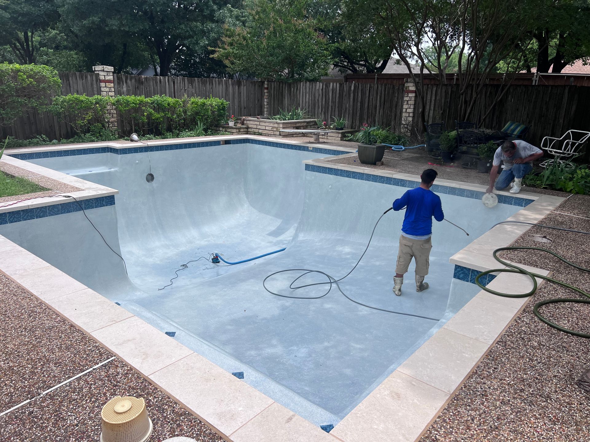 A man is cleaning a swimming pool with a hose