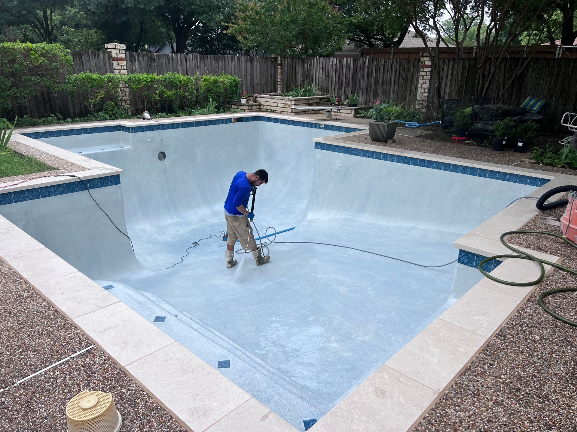 A man is cleaning a swimming pool with a vacuum cleaner.