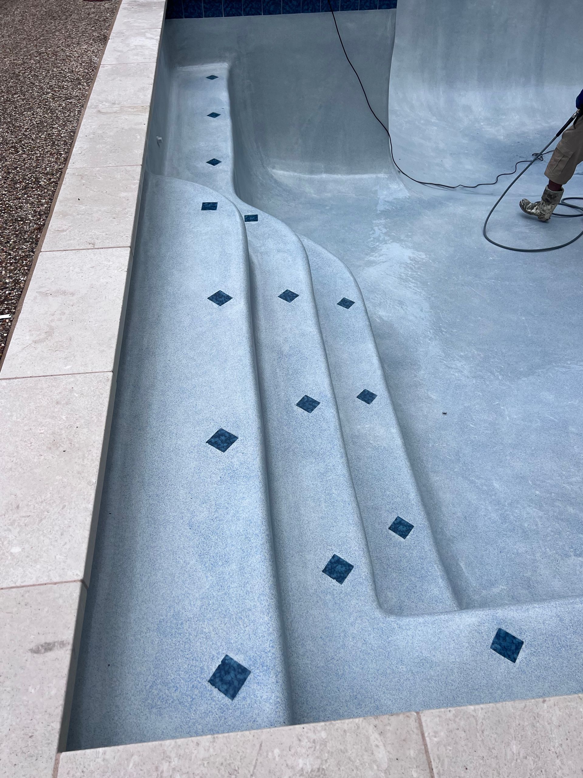 A person is working on the steps of a swimming pool.