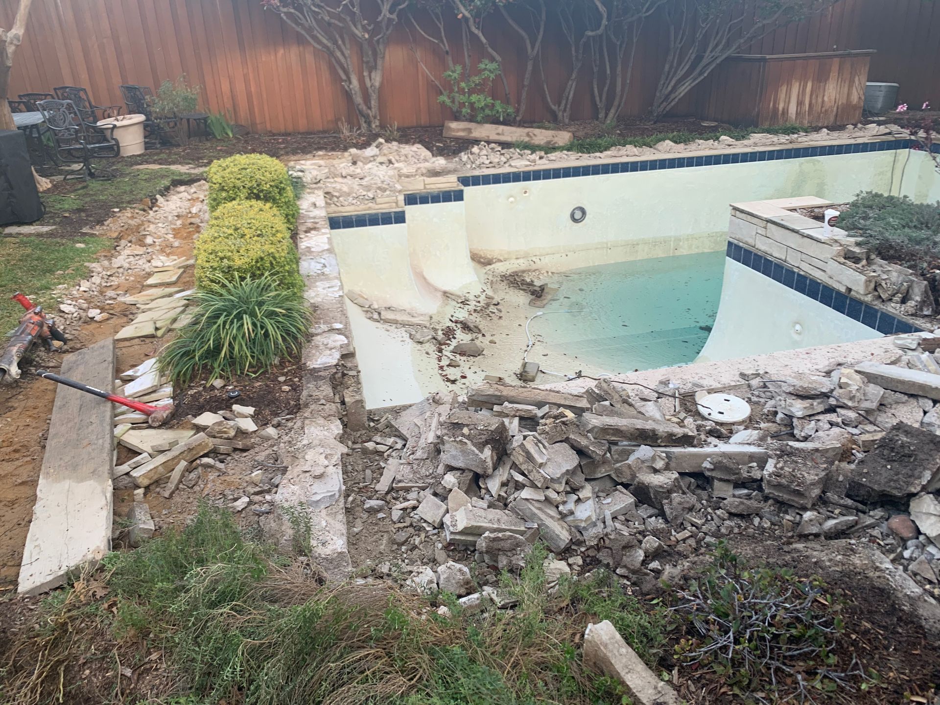 A swimming pool is being demolished in a backyard.
