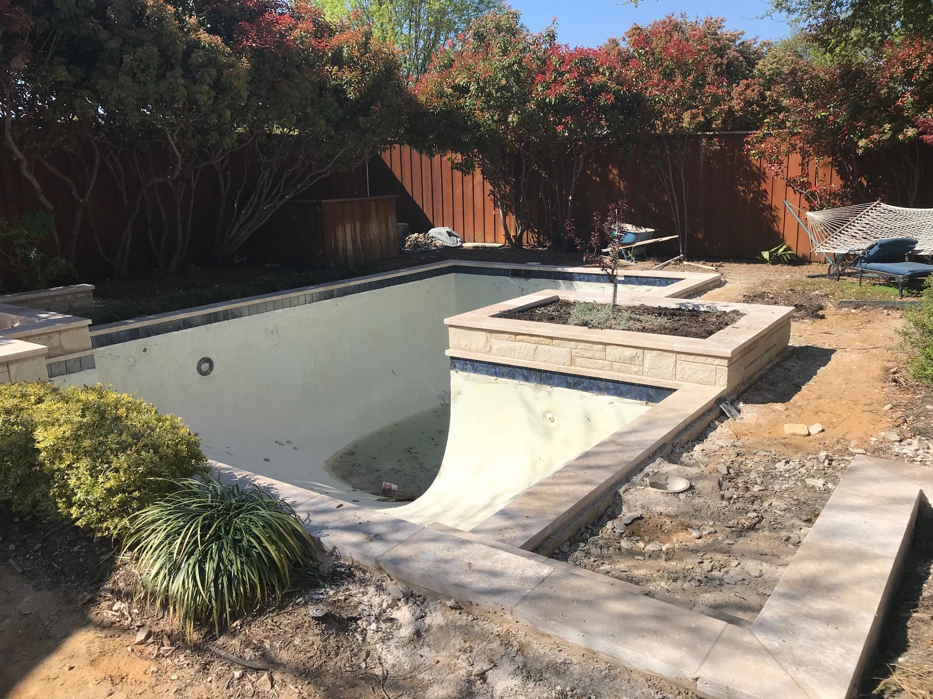 A swimming pool is being built in the backyard of a house.