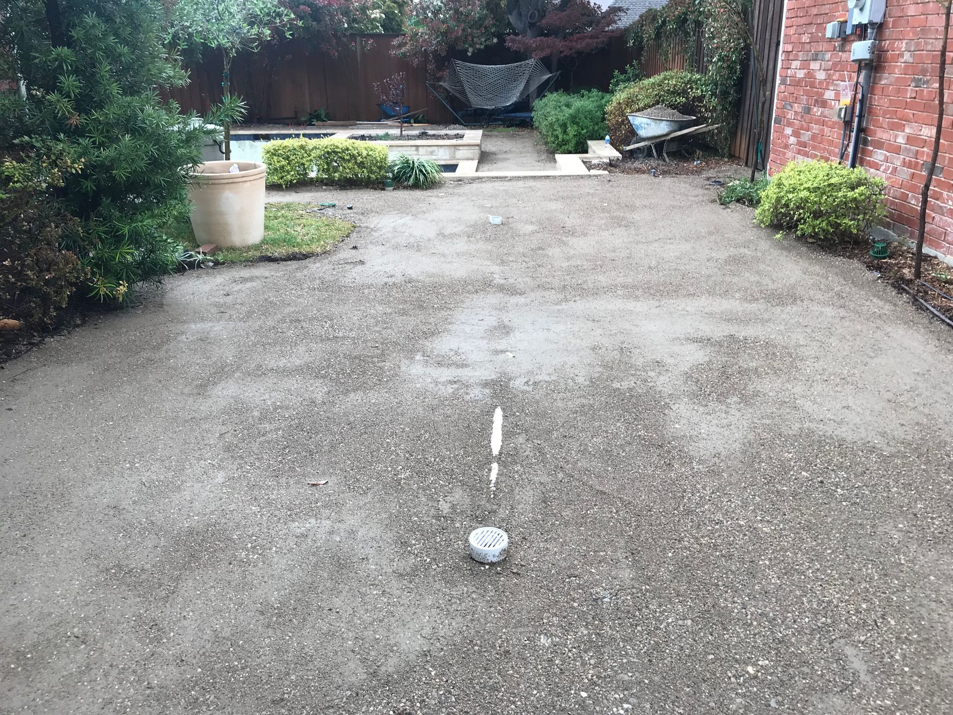A driveway with a brick wall and a pool in the background.