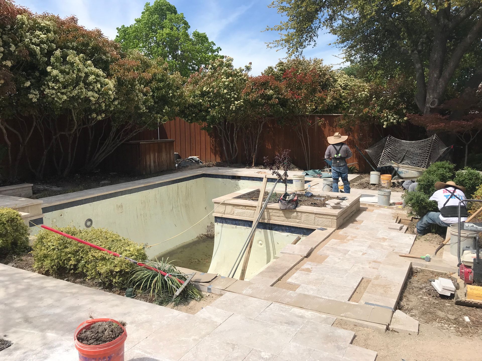 A man is working on a swimming pool in a backyard.
