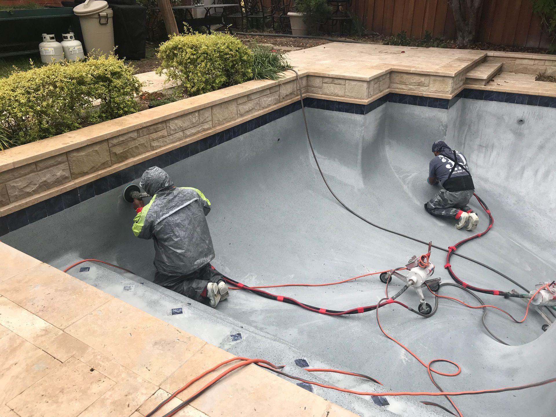 Two men are working on the bottom of a swimming pool.