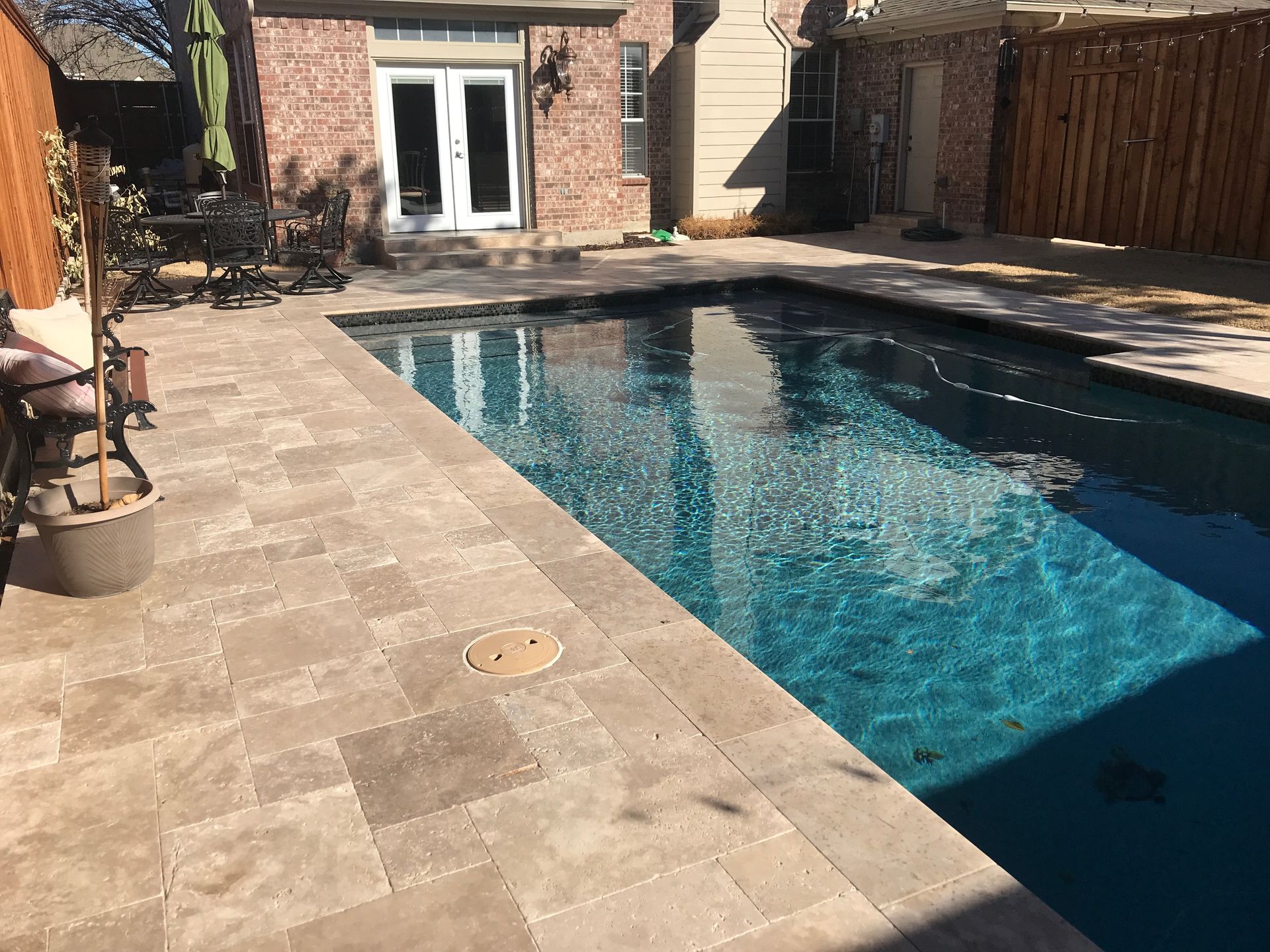 There is a large swimming pool in the backyard of a house.