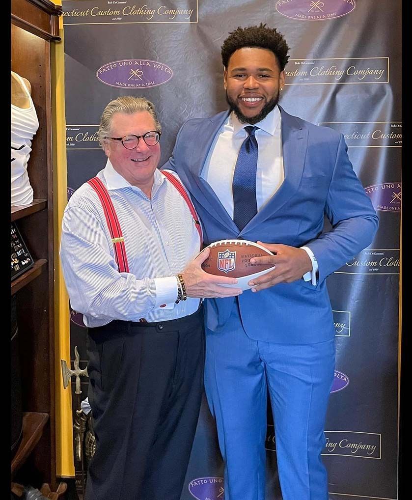 A man in a suit is holding a football next to another man