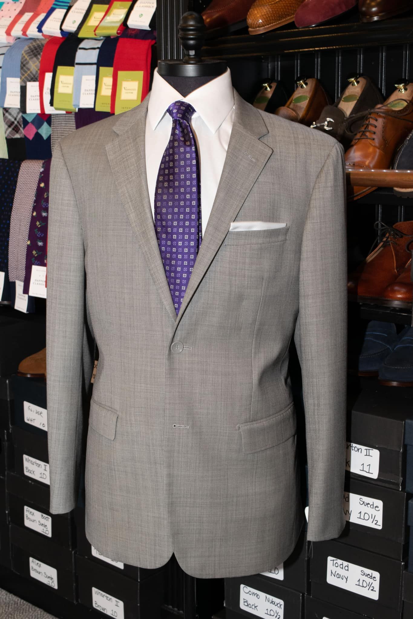 A grey suit with a purple tie is on a mannequin