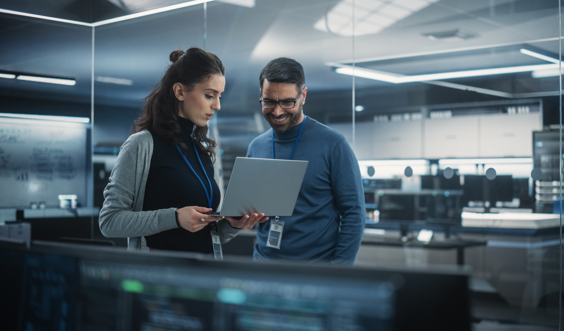 A man and a woman are looking at a laptop in an office.