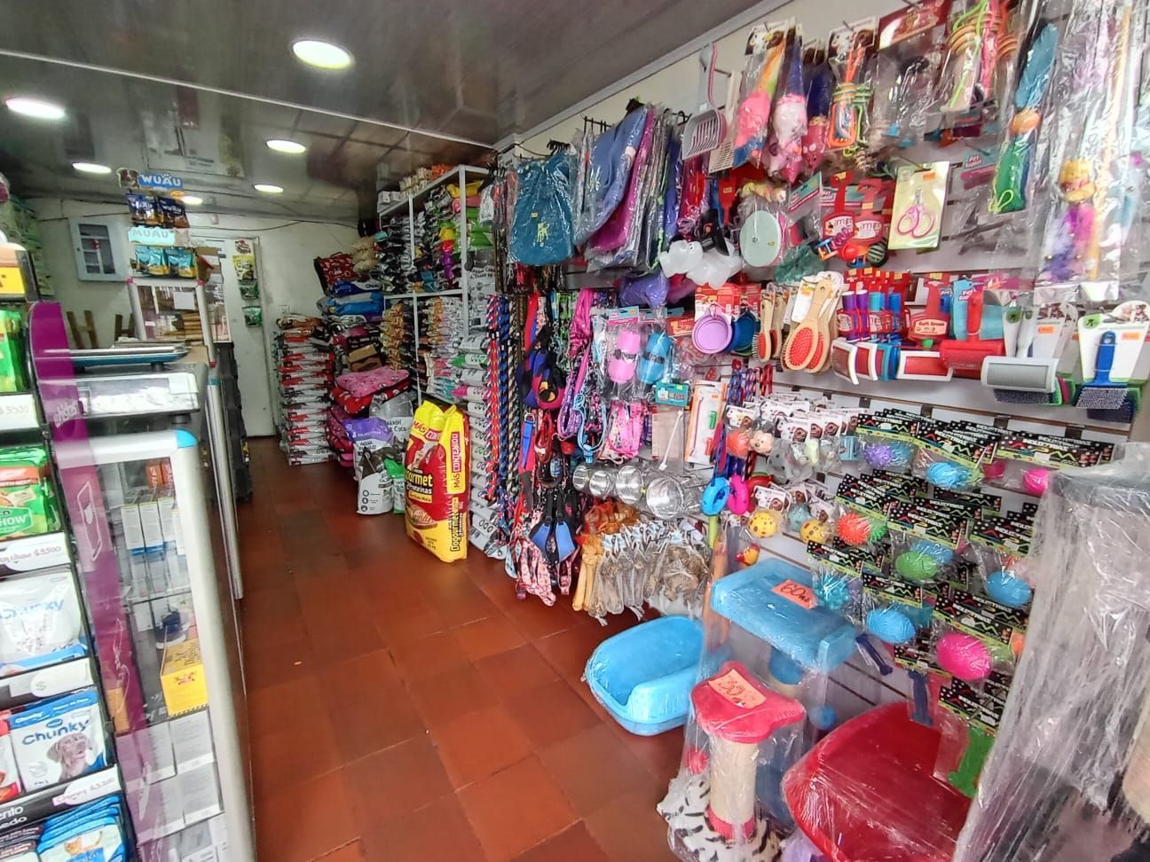 Mano en guante amarillo rociando limpiador desde una botella transparente.