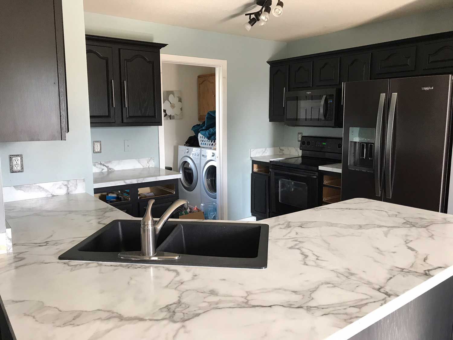 A kitchen with a sink , refrigerator , stove and microwave.