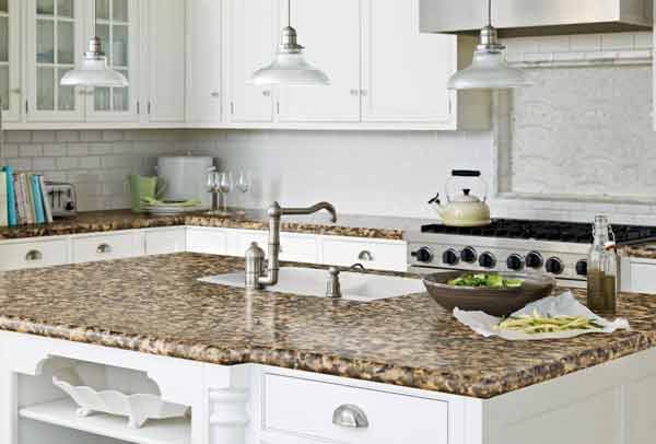 A kitchen with granite counter tops , white cabinets , a stove and a sink.