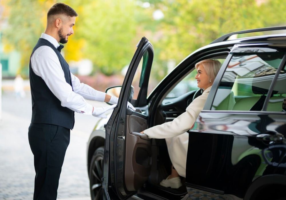 A man is opening the door of a car for a woman.