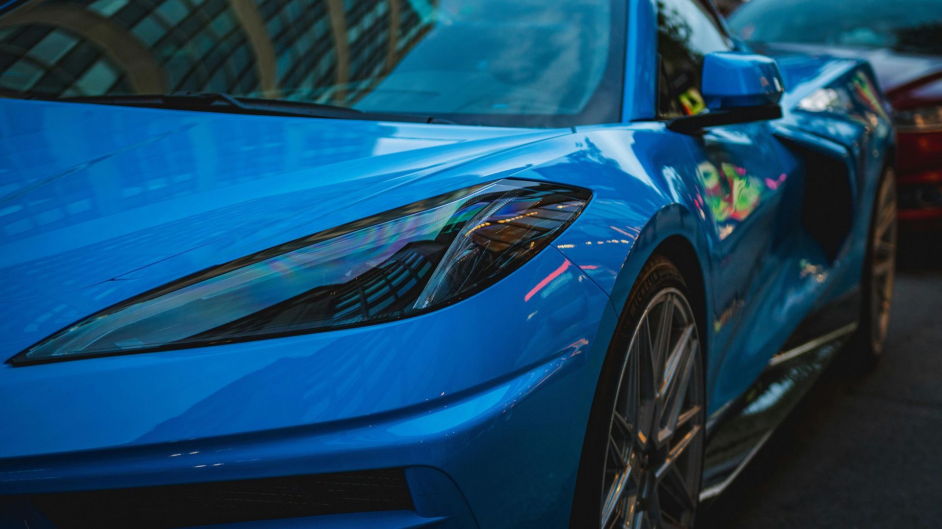 A close up of a blue sports car parked on the side of the road.