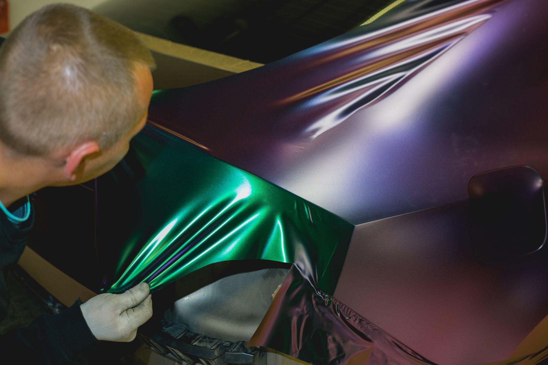 A man is polishing a car door with a machine.