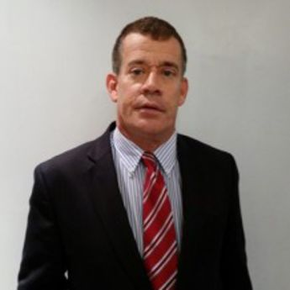 a man in a suit and tie is standing in front of a white wall .