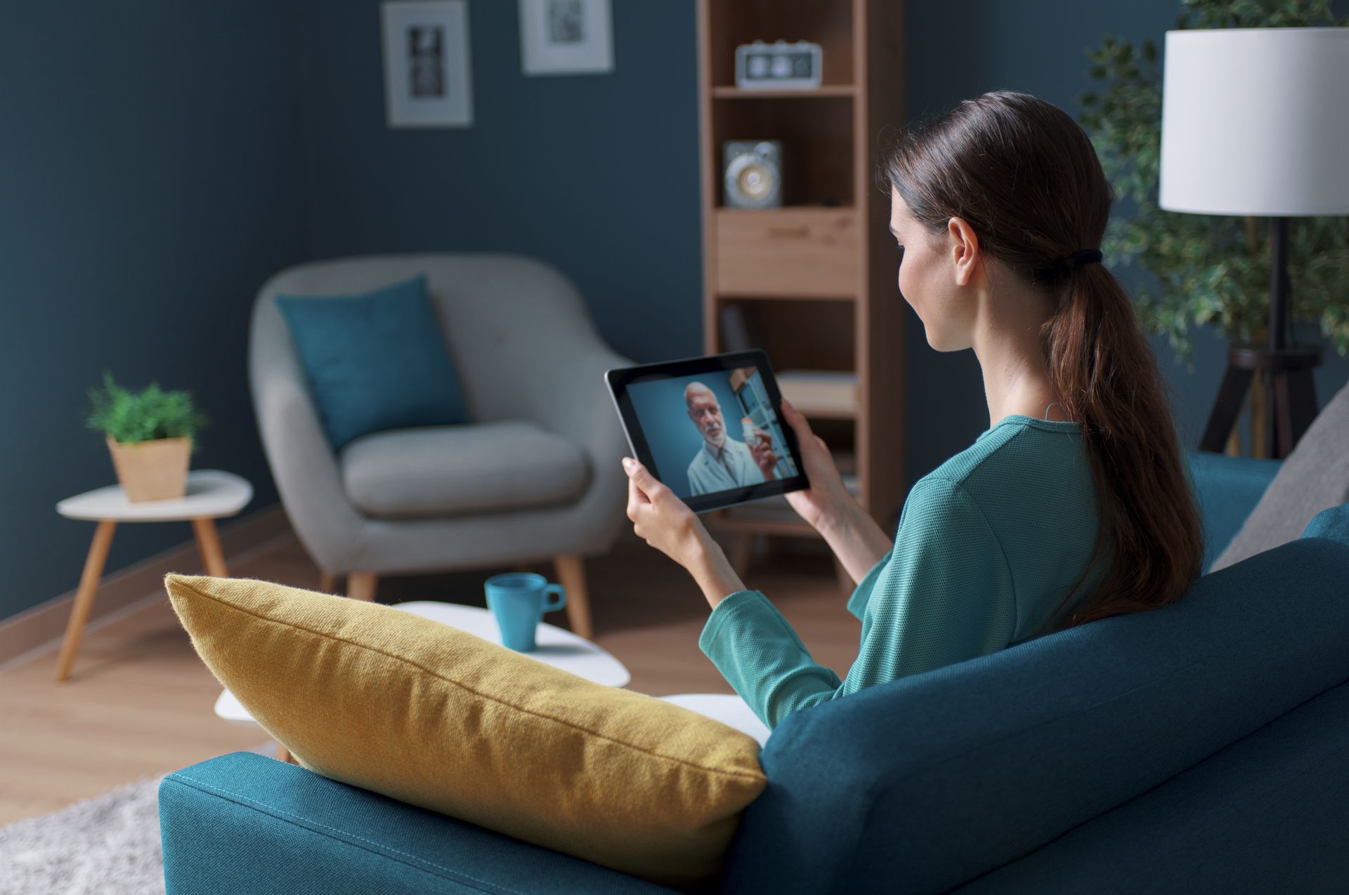 Woman on a couch having a telehealth appointment with her doctor to help manage holiday stress