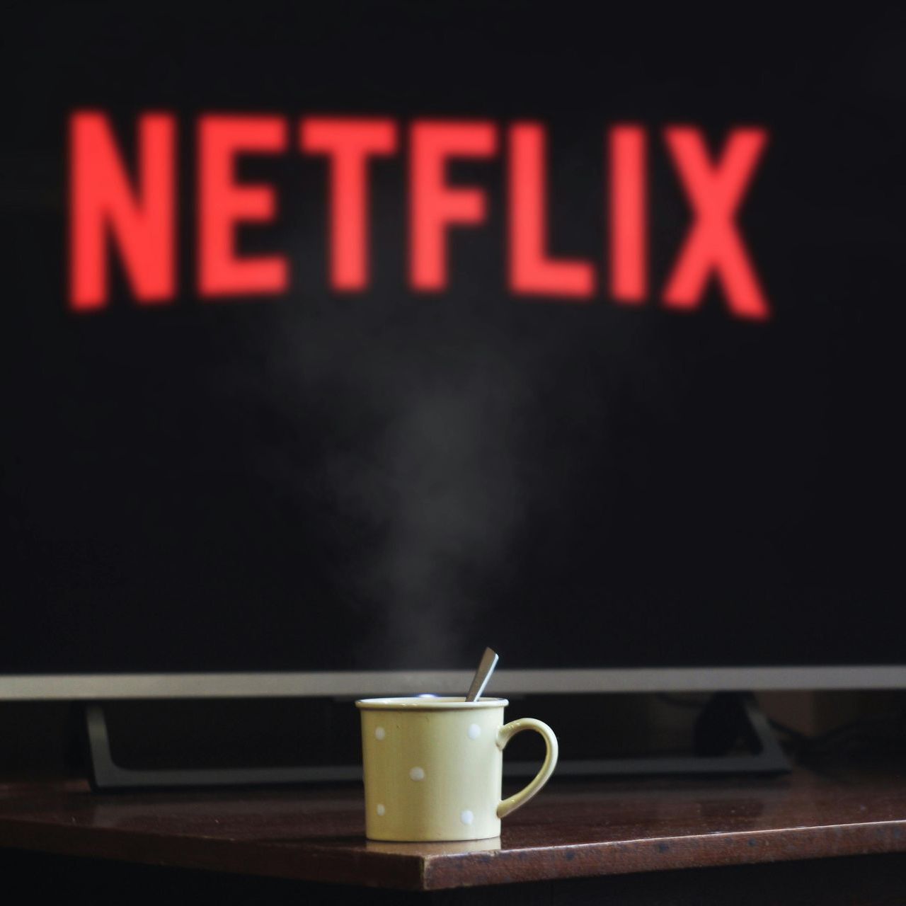 A cup of coffee sits in front of a TV with Netflix logo on screen