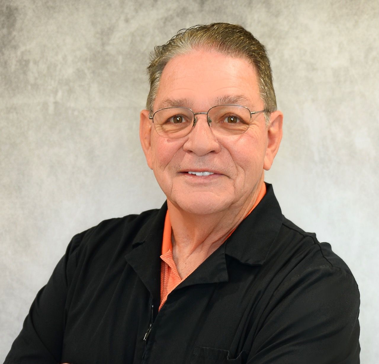 A man wearing glasses and a black shirt smiles for the camera