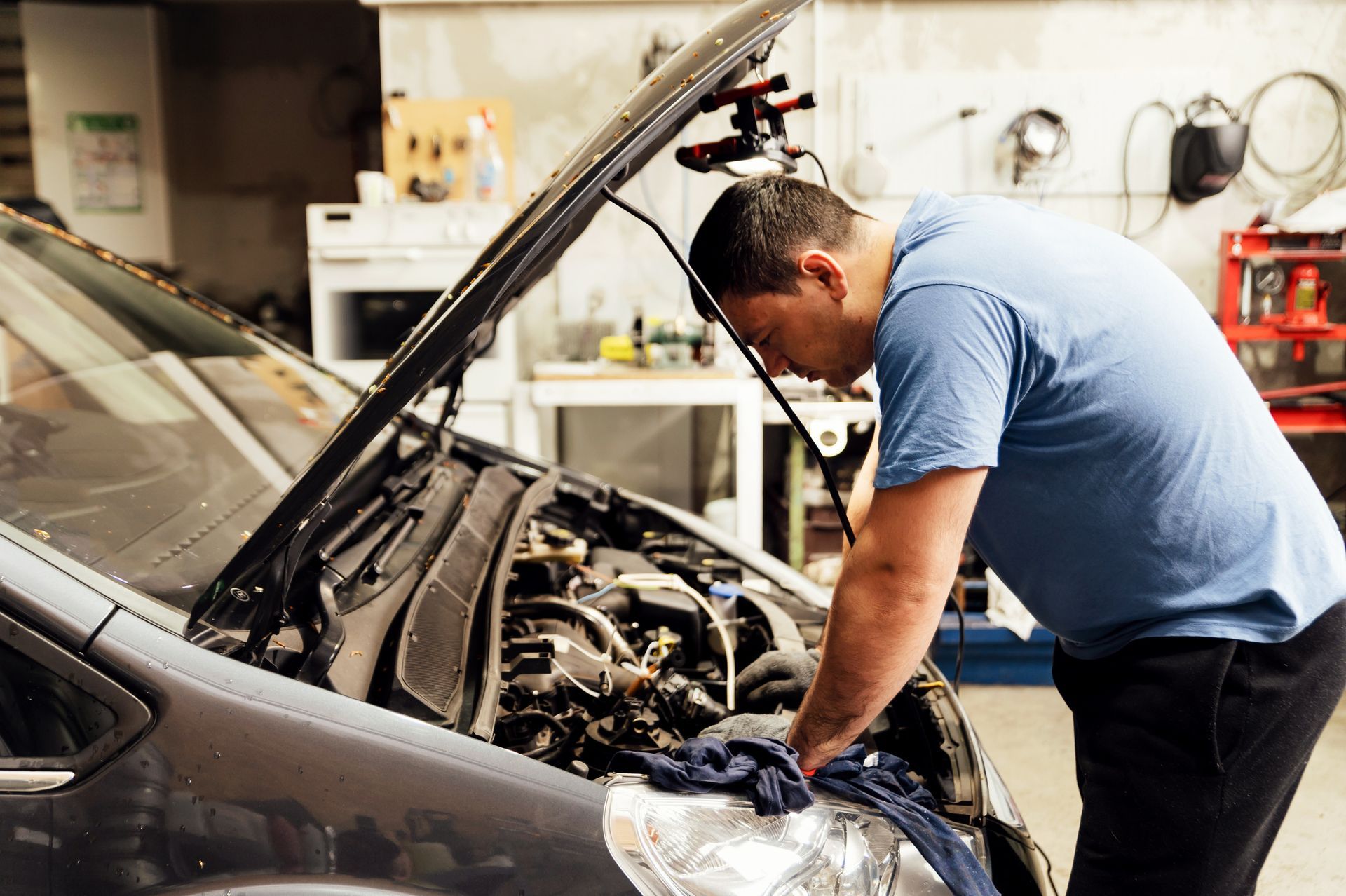 Mechanic works on a car engine in a garage.