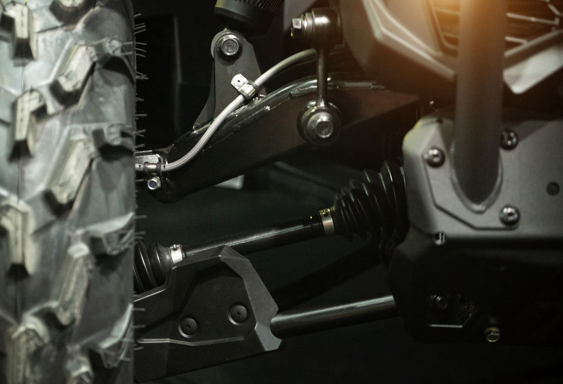 Close-up of a vehicle's suspension system and tire, showing black components and a rugged tire tread.