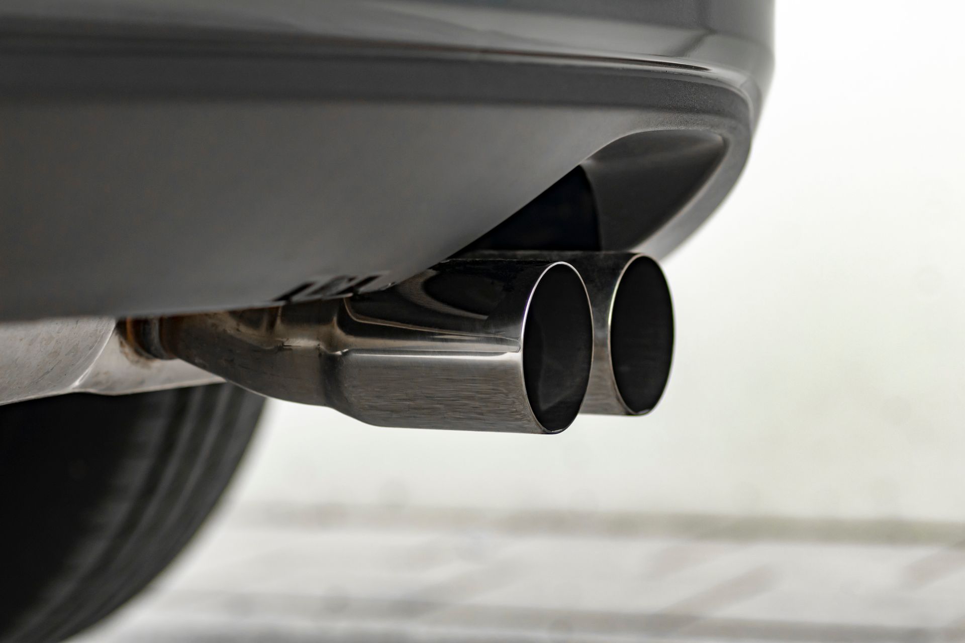 Chrome dual exhaust pipes on the rear of a black car.