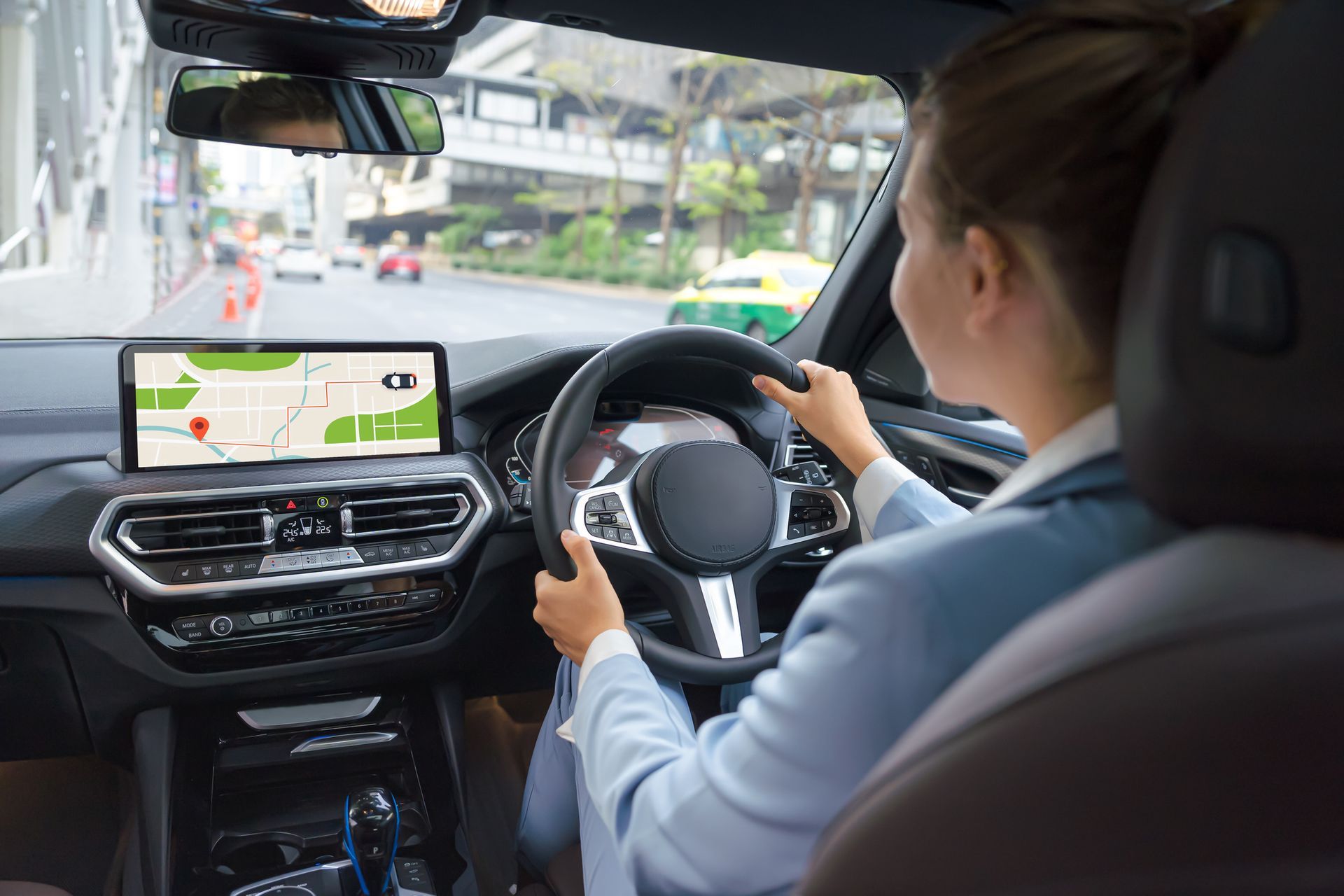 Woman driving car, using navigation system on a city street.