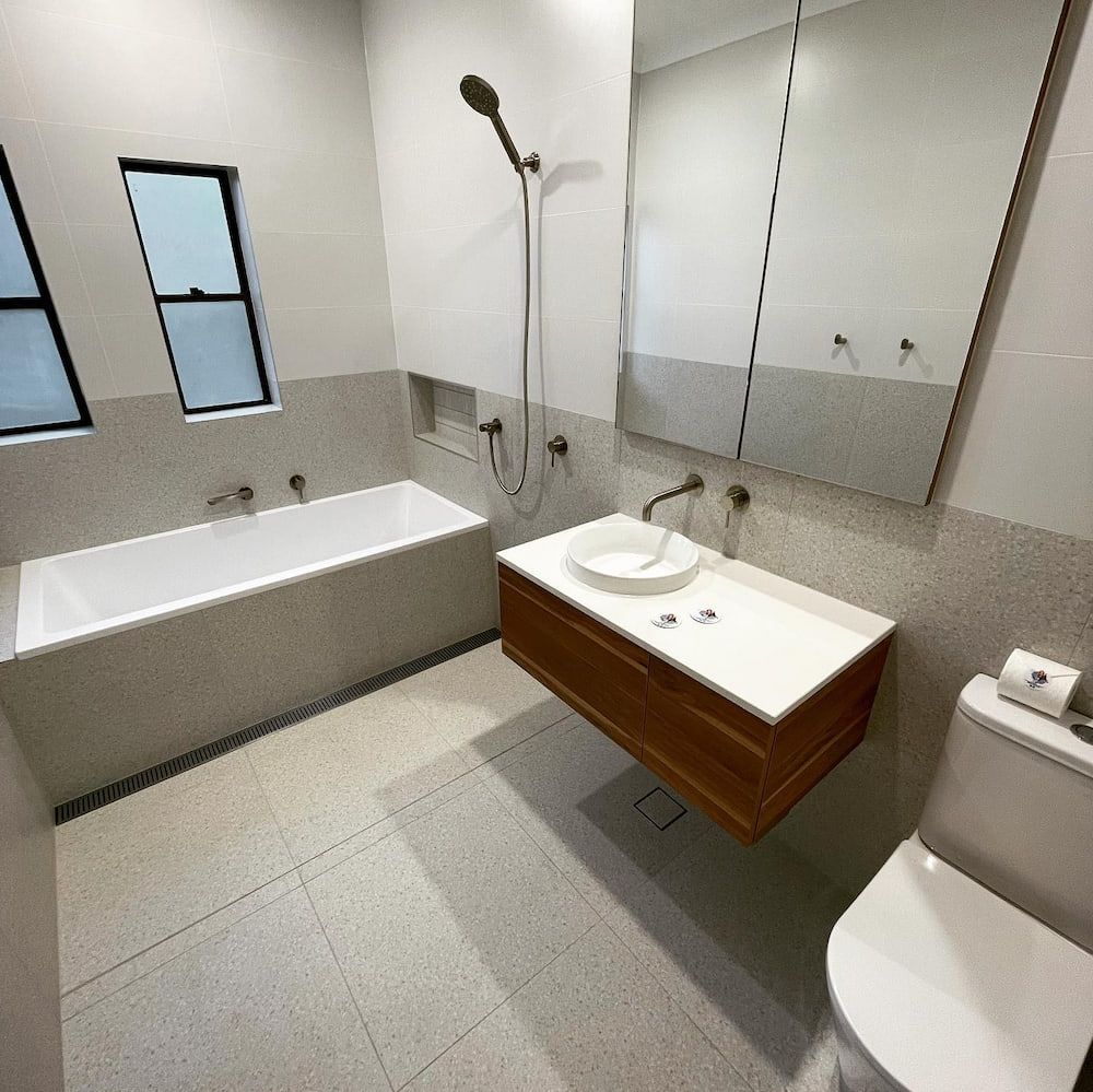 A Bathroom With a Bathtub, Sink, Toilet and Mirror — Firm Built Bathrooms in Wollongong, NSW