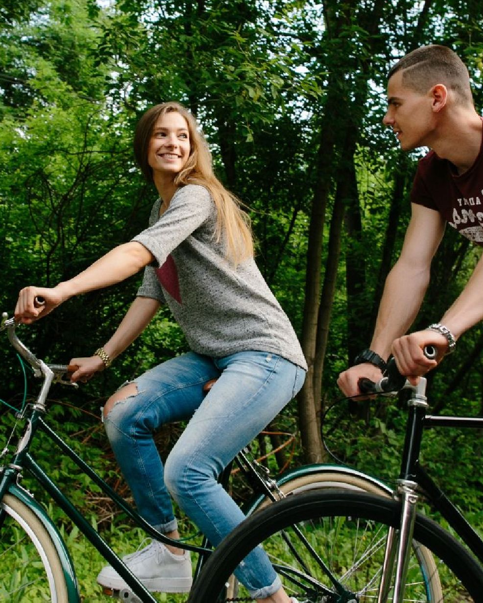 En ung kvinde og ung mand cykler og kigger på hinanden