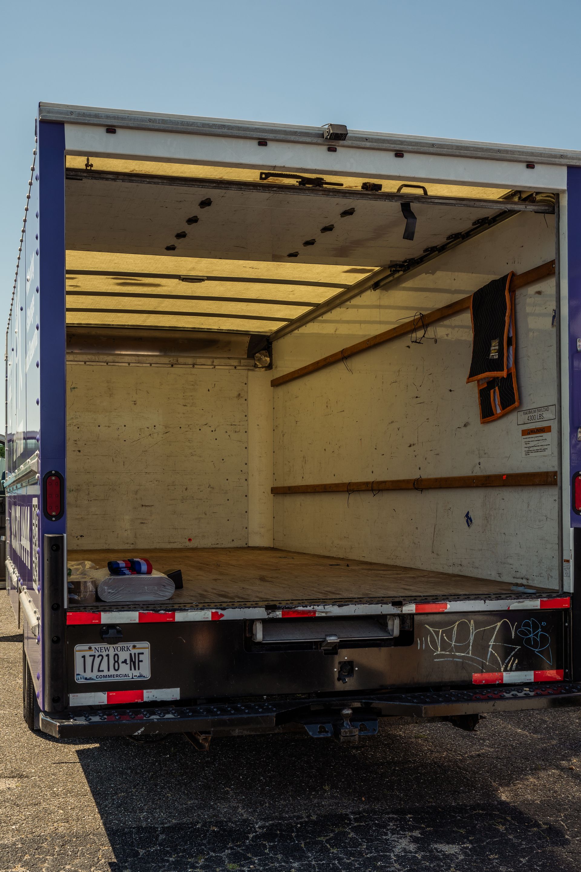 Empty purple and white box truck bed, open in a parking lot.